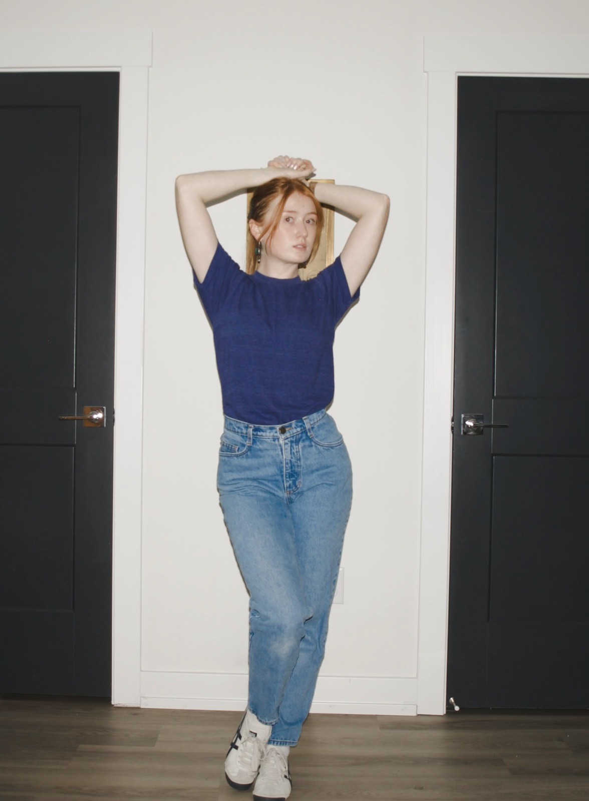 Emma wearing light-wash Los Angeles Apparel relaxed-fit jeans with a blue T-shirt and white sneakers
