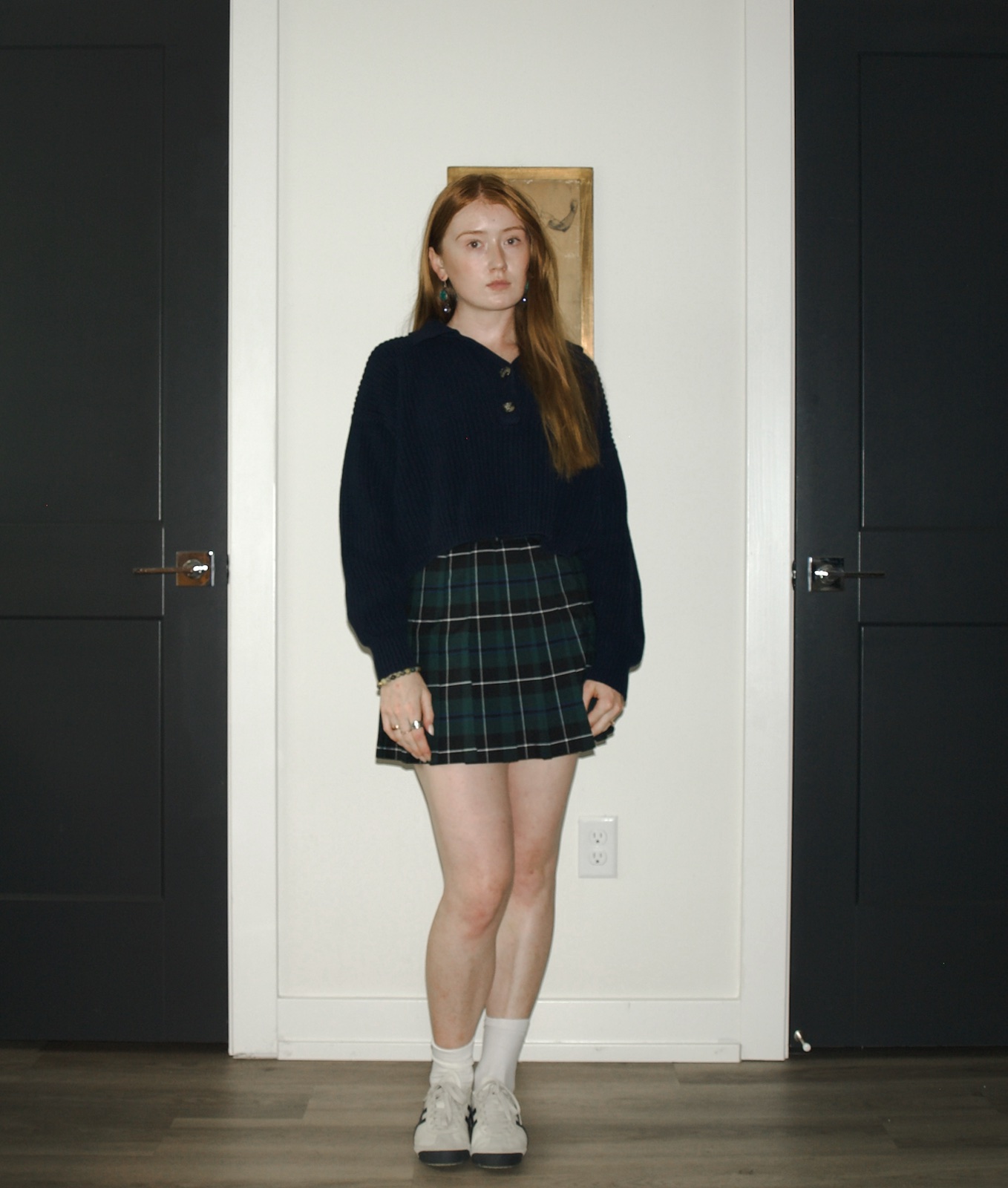 Emma wearing a navy Fisherman cropped polo pullover with a plaid tennis skirt